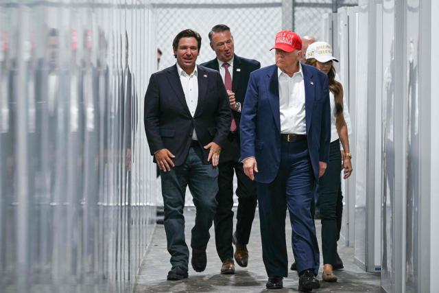 TOPSHOT - US President President Donald Trump (2R), Florida Governor Ron DeSantis (L), and Secretary of Homeland Security Kristi Noem (R) tour a migrant detention center, dubbed "Alligator Alcatraz," located at the site of the Dade-Collier Training and Transition Airport in Ochopee, Florida on July 1, 2025. President Trump is visiting a migrant detention center in a reptile-infested Florida swamp dubbed "Alligator Alcatraz." Trump will attend the opening of the 5,000-bed facility -- located at an abandoned airfield in the Everglades wetlands -- part of his expansion of deportations of undocumented migrants, his spokeswoman said. (Photo by ANDREW CABALLERO-REYNOLDS / AFP)