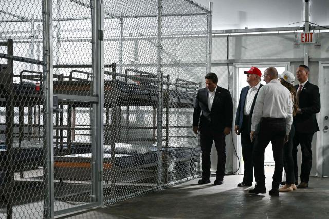 US President President Donald Trump (2L), alongside Florida Governor Ron DeSantis (L), tour a migrant detention center, dubbed "Alligator Alcatraz," located at the site of the Dade-Collier Training and Transition Airport in Ochopee, Florida on July 1, 2025. President Trump is visiting a migrant detention center in a reptile-infested Florida swamp dubbed "Alligator Alcatraz." Trump will attend the opening of the 5,000-bed facility -- located at an abandoned airfield in the Everglades wetlands -- part of his expansion of deportations of undocumented migrants, his spokeswoman said. (Photo by ANDREW CABALLERO-REYNOLDS / AFP)