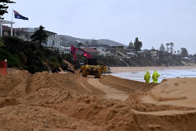 Workers operate heavy machinery to stabilise Wamberal Beach as a low-pressure cyclone lashes the Central Coast, forcing residents to evacuate beachfront homes amid growing erosion fears on July 2, 2025. (Photo by SAEED KHAN / AFP)
