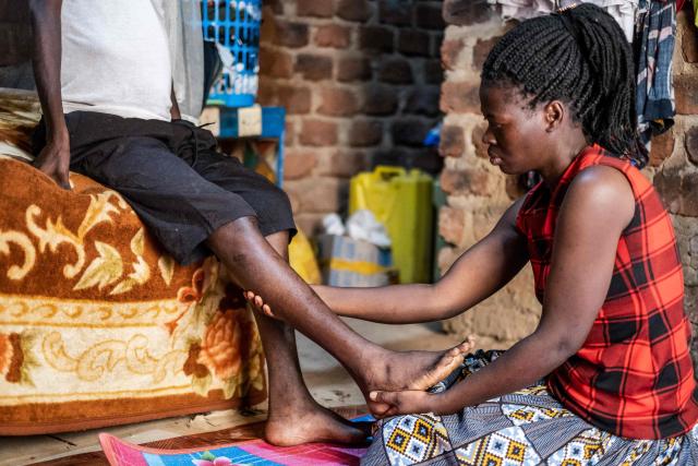 Josephine Namwanjje (R), 28, checks the legs of his brother Jonathan Luzige, a colon cancer patient, at their home in Nabbingo, on June 26, 2025. Hospice Africa Uganda (HAU), founded in 1993 by Dr Anne Merriman, brought holistic end-of-life care to Uganda at a time when it was offered in only three African countries.
By the time Merriman died in May 2025, aged 90, she had treated more than 40,000 patients in Uganda and her model had spread to 37 African countries. (Photo by Badru Katumba / AFP)
