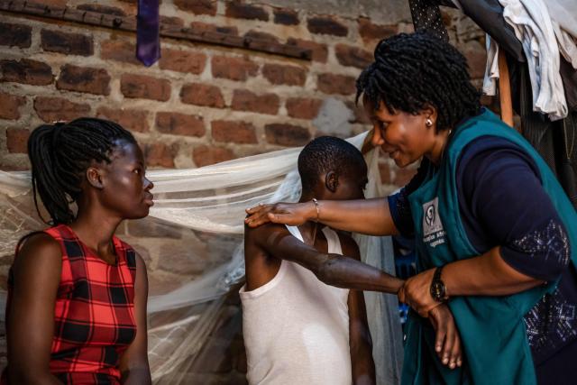 Jane Mwesige, a nurse at Hospice Africa Uganda (HAU), massages the arms of patient Jonathan Luzige while speaking to his sister during a home visit in Nabbingo, on June 26, 2025. Hospice Africa Uganda (HAU), founded in 1993 by Dr Anne Merriman, brought holistic end-of-life care to Uganda at a time when it was offered in only three African countries.
By the time Merriman died in May 2025, aged 90, she had treated more than 40,000 patients in Uganda and her model had spread to 37 African countries. (Photo by Badru Katumba / AFP)