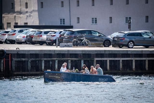 People make their way along one of Copenhagen's canals in a rental boat from GoBoat in the Danish capital on July 23, 2021. From mid-June until late August, the CopenPay initiative offers around 100 activities, including motorboat rental company GoBoat, in exchange for free or reduced prices on a selection of experiences. (Photo by Emil Helms / Ritzau Scanpix / AFP) / Denmark OUT