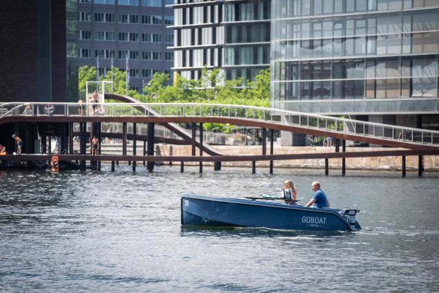People make their way along one of Copenhagen's canals in a rental boat from GoBoat in the Danish capital on July 23, 2021. From mid-June until late August, the CopenPay initiative offers around 100 activities, including motorboat rental company GoBoat, in exchange for free or reduced prices on a selection of experiences. (Photo by Emil Helms / Ritzau Scanpix / AFP) / Denmark OUT