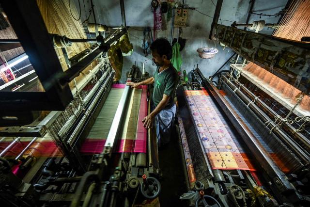 (FILES) In this photograph taken on November 20, 2021, a worker uses a power loom to weave a Banarasi silk sari at a workshop in Varanasi. Indian exporters are anxiously eyeing the possible reintroduction of Donald Trump's punishing tariffs on the second week of July 2025, though many hold out hope for a last-minute reprieve. The US president's April 2 "Liberation Day" announcement of swingeing levies on dozens of key trading partners sent shockwaves through capitals before he announced a pause for negotiations, which ends on July 9, 2025. New Delhi and Washington have been locked in multiple rounds of talks, with hopes for an interim pact to avert the 26 percent "reciprocal" tolls meted out to India. (Photo by Money SHARMA / AFP)