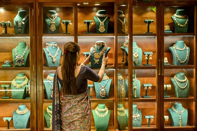 (FILES) An employee arranges gold jewellery on display at a store in Amritsar on April 2, 2025. Indian exporters are anxiously eyeing the possible reintroduction of Donald Trump's punishing tariffs on the second week of July 2025, though many hold out hope for a last-minute reprieve. The US president's April 2 "Liberation Day" announcement of swingeing levies on dozens of key trading partners sent shockwaves through capitals before he announced a pause for negotiations, which ends on July 9, 2025. New Delhi and Washington have been locked in multiple rounds of talks, with hopes for an interim pact to avert the 26 percent "reciprocal" tolls meted out to India. (Photo by Narinder NANU / AFP)