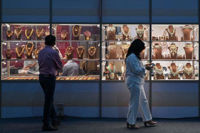 (FILES) Visitors walk past jewellery on display during the 1st India International Jewellery Show organised by the Gem and Jewellery Export Promotion Council (GJEPC) in Bengaluru on March 17, 2023. Indian exporters are anxiously eyeing the possible reintroduction of Donald Trump's punishing tariffs on the second week of July 2025, though many hold out hope for a last-minute reprieve. The US president's April 2 "Liberation Day" announcement of swingeing levies on dozens of key trading partners sent shockwaves through capitals before he announced a pause for negotiations, which ends on July 9, 2025. New Delhi and Washington have been locked in multiple rounds of talks, with hopes for an interim pact to avert the 26 percent "reciprocal" tolls meted out to India. (Photo by Manjunath KIRAN / AFP)