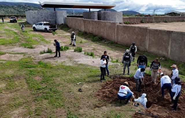 Aerial view of members of the "Guerreros Buscadores" collective, guarded by National Guard personnel, searching human remains in a clandestine grave in Zapopan, Jalisco State, Mexico, on July 1, 2025, where the public prosecutor's office had concluded its search efforts. On June 26, Mexican authorities discovered the bodies of 34 people in a mass grave in a western region wracked by criminal violence, the state prosecutor's office said. The remains were found during construction work in Zapopan in Jalisco state, home to one of the country's most powerful drug cartels, prosecutor Salvador Gonzalez told a news conference. (Photo by AFP)