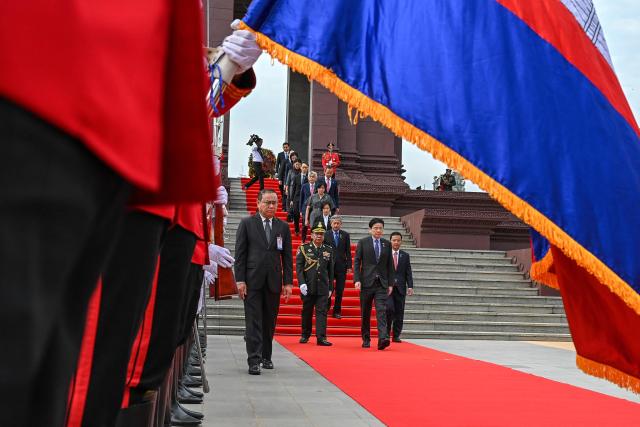 Singapore’s Prime Minister Lawrence Wong (C) inspects a guard of honour at the Independence Monument in Phnom Penh on July 2, 2025. (Photo by TANG CHHIN Sothy / AFP)