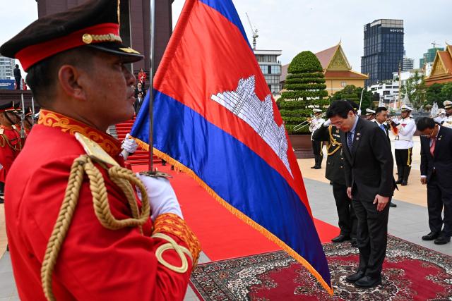 Singapore’s Prime Minister Lawrence Wong (C) inspects a guard of honour at the Independence Monument in Phnom Penh on July 2, 2025. (Photo by TANG CHHIN Sothy / AFP)