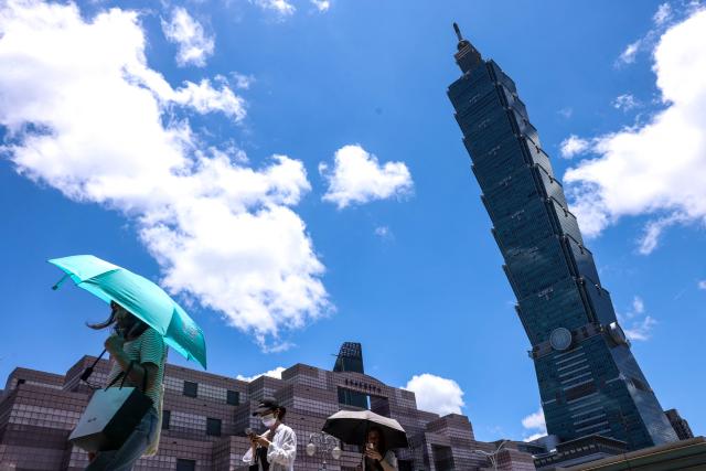 People use umbrellas to shelter from the sun as they walk along a street on a hot day in Taipei on July 2, 2025. (Photo by I-Hwa Cheng / AFP)