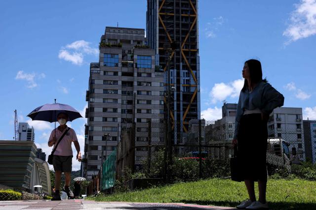 A man uses an umbrella to shelter from the sun as he walks along a street on a hot day in Taipei on July 2, 2025. (Photo by I-Hwa Cheng / AFP)