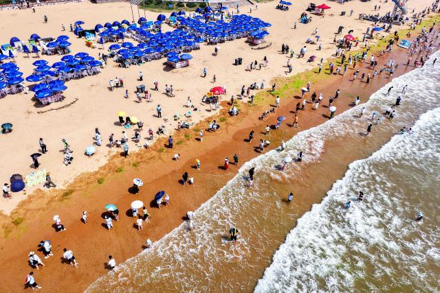 TOPSHOT - An aerial view shows people cooling off on a beach in Qingdao, in eastern China's Shandong province on July 1, 2025. (Photo by AFP) / China OUT