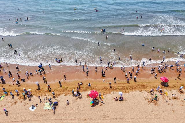 An aerial view shows people cooling off on a beach in Qingdao, in eastern China's Shandong province on July 1, 2025. (Photo by AFP) / China OUT