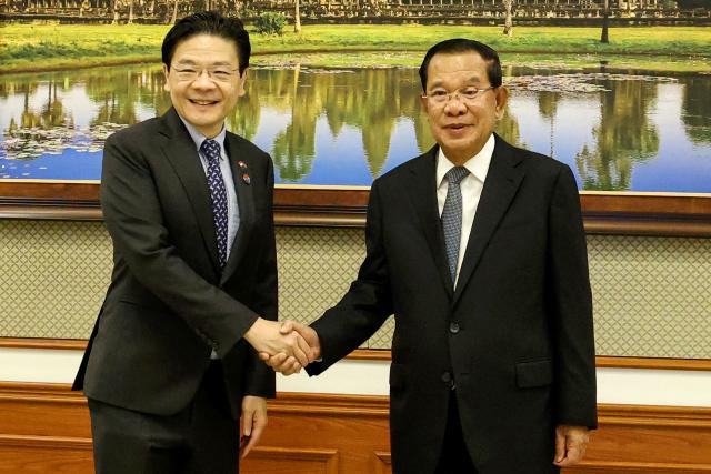This pool photo taken and released on July 2, 2025 by Agence Kampuchea Presse (AKP) shows Cambodia's Senate President Hun Sen (R) shaking hands with Singapore's Prime Minister Lawrence Wong (L) during a meeting at the Senate in Phnom Penh. (Photo by -STR / POOL / AFP)