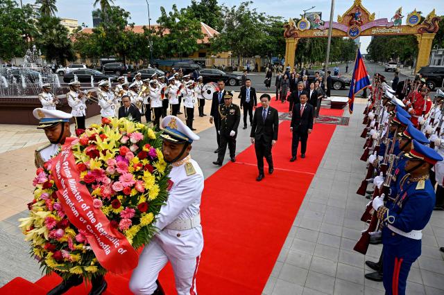 Singapore's Prime Minister Lawrence Wong (C) walks past the honor guard at the Independence Monument in Phnom Penh on July 2, 2025. (Photo by TANG CHHIN Sothy / AFP)