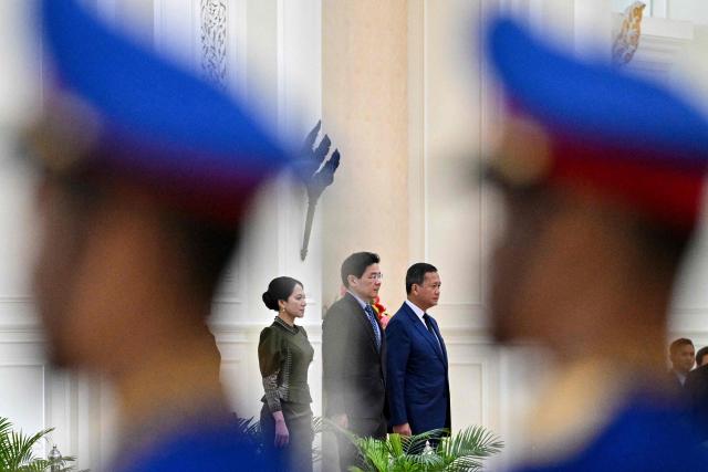 Cambodia's Prime Minister Hun Manet (Center R) and Singapore's Prime Minister Lawrence Wong (Center L) listen to their national anthems at the Peace Palace in Phnom Penh on July 2, 2025. (Photo by TANG CHHIN Sothy / AFP)