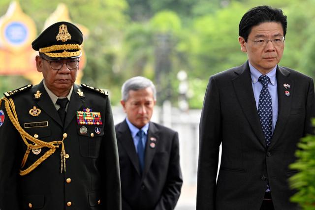 Singapore's Prime Minister Lawrence Wong (R) pays his respects next to Cambodian General Pou Saboddy (L) at the Independence Monument in Phnom Penh on July 2, 2025. (Photo by TANG CHHIN Sothy / AFP)