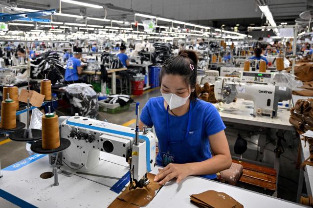 A worker stitches apparels at a garment factory in Vietnam's Thai Nguyen Province on July 2, 2025. Vietnam, a global manufacturing hub dependent on exports, faces a potential "reciprocal tariff" hike from 10 to 46 percent without a US trade deal. (Photo by Nhac NGUYEN / AFP)