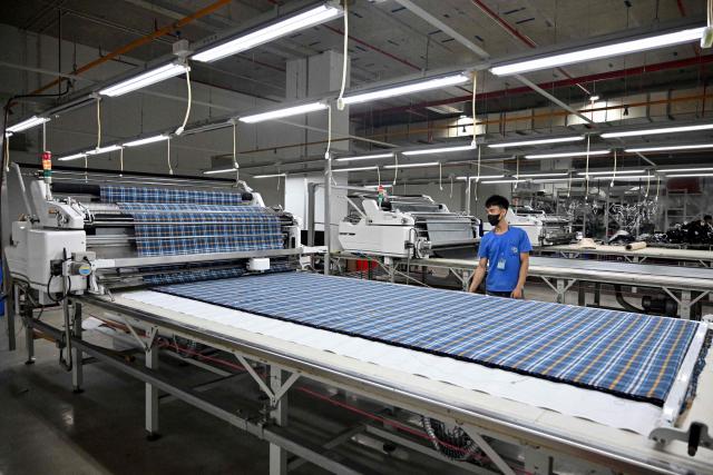A worker uses an automatic fabric cutting machine at a garment factory in Vietnam's Thai Nguyen Province on July 2, 2025. Vietnam, a global manufacturing hub dependent on exports, faces a potential "reciprocal tariff" hike from 10 to 46 percent without a US trade deal. (Photo by Nhac NGUYEN / AFP)