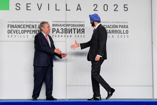 In this picture taken on June 30, 2025, United Nations Secretary-General Antonio Guterres (L) greets World Bank Group President Ajay Banga before a family photo with the rest of heads of state and representatives attending the United Nations 4th International Conference on Financing and Development in Seville. More than 100 nations attending a UN aid conference pledged this week to help defuse the ticking time bomb of developing countries' ballooning debt, but deciding how is proving more divisive. The United Nations puts the annual funding deficit for aid at more than $4 trillion, with chilling consequences for health, education and humanitarian programmes in the poorest countries. (Photo by CRISTINA QUICLER / AFP)