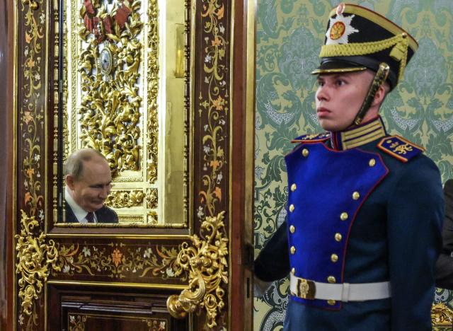Russian President Vladimir Putin is reflected in a mirror while walking past a guard of honour during a meeting with his Kyrgyz counterpart at the Kremlin in Moscow on July 2, 2025. (Photo by Maxim Shemetov / POOL / AFP)