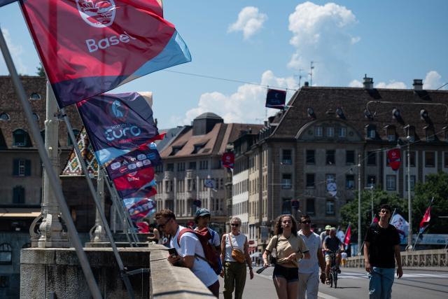Flags of the UEFA European Women's Championship fly as people walk on a bridge in Basel on July 2, 2025. (Photo by Miguel MEDINA / AFP)