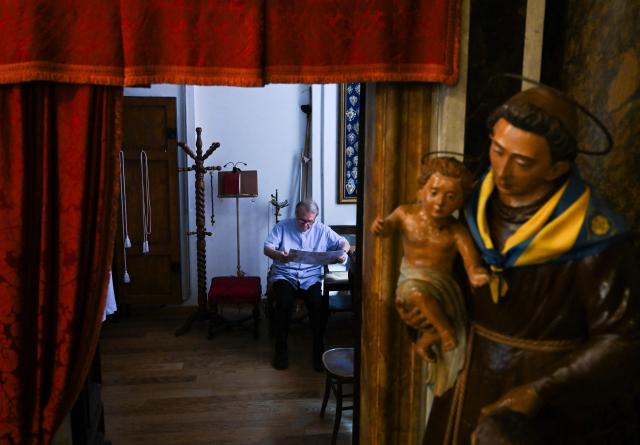 A priest member of the Tartuca (Turtle) district reads newspaper in the sacristy ahead of the historical Italian horse race "Palio di Siena", on July 2, 2025 in Siena, Tuscany. (Photo by Stefano RELLANDINI / AFP)