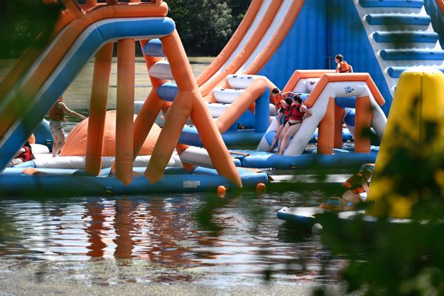People stand on an inflatable structure at a water sports leisure centre in Basse-Ham, north-eastern France, on July 2, 2025, as a heatwave hits Europe. (Photo by Jean-Christophe VERHAEGEN / AFP)