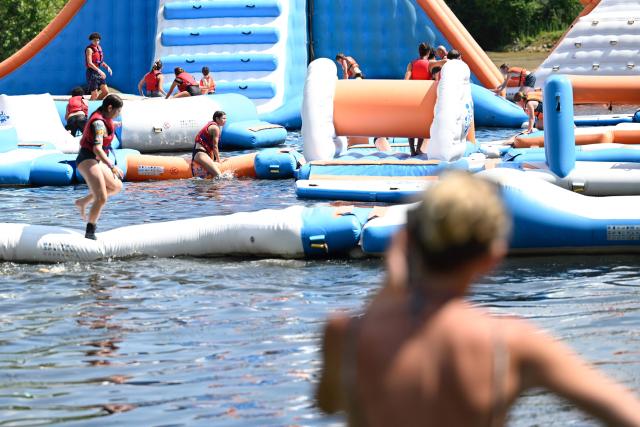 People stand on an inflatable structure at a water sports leisure centre in Basse-Ham, north-eastern France, on July 2, 2025, as a heatwave hits Europe. (Photo by Jean-Christophe VERHAEGEN / AFP)