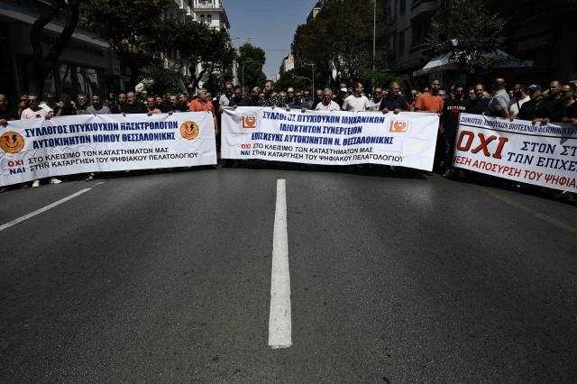 Owners of Greece Auto Services hold a banner as they protest in Thessaloniki on July 2, 2025. Car repair shops, car washes, parking facilities, and vehicle rental businesses across Greece have begun rolling 24-hour strikes in protest against the compulsory implementation of a new digital customer registry, which came into effect on July 1. (Photo by Sakis Mitrolidis / AFP)