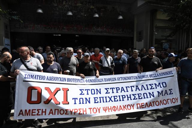 Owners of Greece Auto Services hold a banner reading 'no to the strangulation of our businesses, immediate withdrawal of digital clientele' during a demonstration in Thessaloniki on July 2, 2025. Car repair shops, car washes, parking facilities, and vehicle rental businesses across Greece have begun rolling 24-hour strikes in protest against the compulsory implementation of a new digital customer registry, which came into effect on July 1. (Photo by Sakis Mitrolidis / AFP)