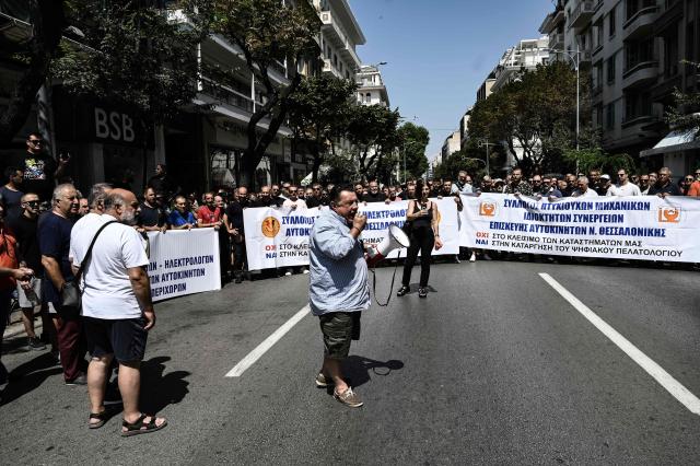Owners of Greece Auto Services hold a banner as they protest in Thessaloniki on July 2, 2025. Car repair shops, car washes, parking facilities, and vehicle rental businesses across Greece have begun rolling 24-hour strikes in protest against the compulsory implementation of a new digital customer registry, which came into effect on July 1. (Photo by Sakis Mitrolidis / AFP)