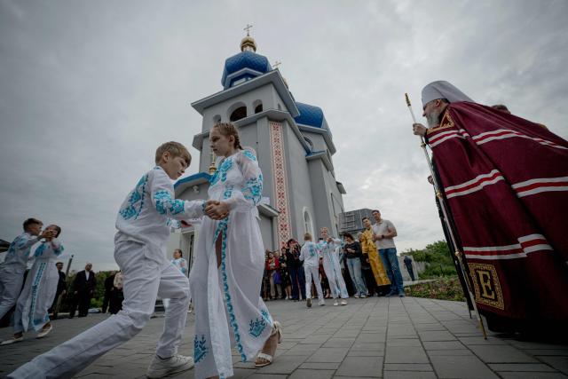 Children dance during a consecration ceremony of a newly built church in the village of Koviagy, Kharkiv region, on July 2, 2025, amid the Russian invasion of Ukraine. (Photo by Ivan SAMOILOV / AFP)