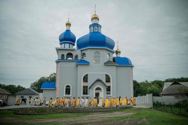 A procession of clergymen circle around a newly built church during it's consecration ceremony, in the village of Koviagy, Kharkiv region, on July 2, 2025, amid the Russian invasion of Ukraine. (Photo by Ivan SAMOILOV / AFP)