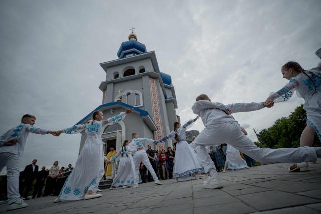 Children dance during a consecration ceremony of a newly built church in the village of Koviagy, Kharkiv region, on July 2, 2025, amid the Russian invasion of Ukraine. (Photo by Ivan SAMOILOV / AFP)