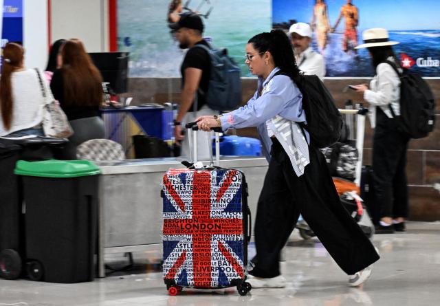 A woman carries her luggage at Jose Marti International Airport in Havana on July 2, 2025. Stricter protocols will characterize the actions promoted by the National Drug Observatory (OND), presented by Cuba on Wednesday at Havana International Airport, with the aim of strengthening the fight against this scourge. (Photo by YAMIL LAGE / AFP)
