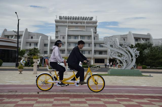 Domestic tourists ride a bicycle at Wonsan Kalma Coastal Tourist Area in Wonsan, North Korea's Kangwon Province on July 2, 2025. North Korea opened a massive resort area on its east coast, state media said on July 2, with the tourism pet project of leader Kim Jong Un reportedly set to welcome Russian guests later this month. (Photo by KIM Won Jin / AFP)