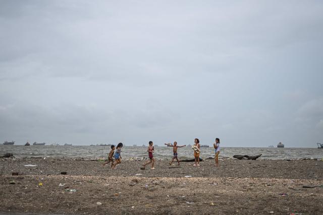 Children play along Manila Bay on July 3, 2025. (Photo by Jam STA ROSA / AFP)