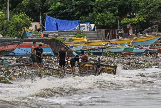 People collects items along Manila Bay on July 3, 2025. (Photo by Jam STA ROSA / AFP)
