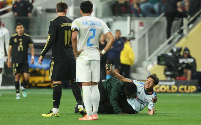 A fan smiles as he he tackled by security after running on the field to get photos of the players during the CONCACAF gold cup semi-final football match between Mexico and Honduras at Levi's Stadium in Santa Clara, California on July 2, 2025. (Photo by Patrick T. Fallon / AFP)