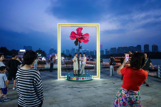 People take photos with a flower installation in Shenyang, in northeastern China's Liaoning province on July 2, 2025. (Photo by AFP) / China OUT