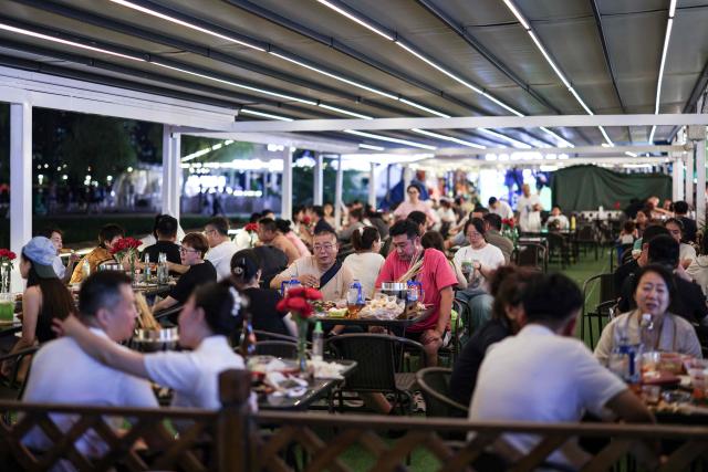 People dine in at a night market in Shenyang, in northeastern China's Liaoning province on July 2, 2025. (Photo by AFP) / China OUT