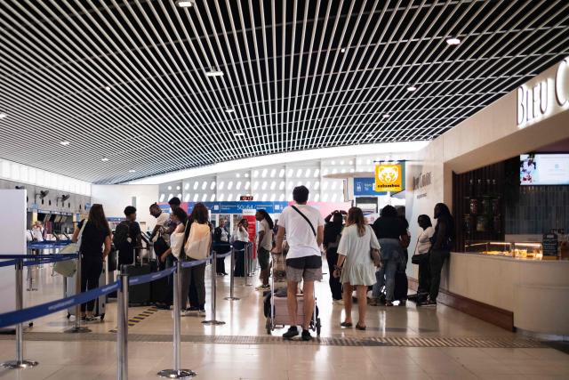 Passengers wait with their luggages at the hall of the international terminal during a control operation against drug trafficking at the Maryse Conde airport, in Les Abymes, on the French Caribbean island of Guadeloupe on July 2, 2025. (Photo by Carla Bernhardt / AFP)