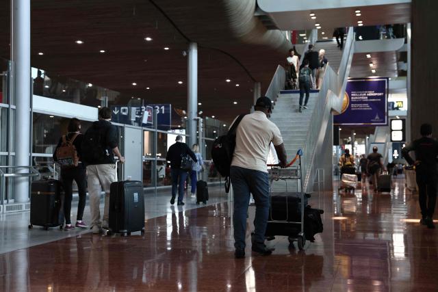 Passengers carry their luggages at Roissy Charles-de-Gaulle airport, outside Paris, on July 3, 2025, as French air traffic controllers launched a two-day strike to demand better working conditions, disrupting travel for tens of thousands of people at the start of a summer holiday season. (Photo by Thibaud MORITZ / AFP)