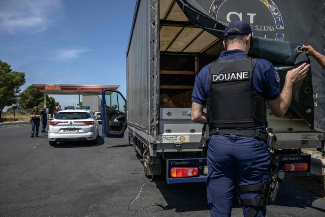 French customs police search a vehicle at a rest stop on the A9 motorway between Narbonne and the Spanish border, on June 19, 2025. On the A9 motorway, which runs along the Mediterranean coast from Spain, Narbonne customs officers, flashing their lights and blaring their sirens, pull over suspicious vehicles in search of cocaine traffickers who are increasingly crossing the Franco-Spanish border, where more than 65 percent of the drugs supplying France already transit. (Photo by Ed JONES / AFP)