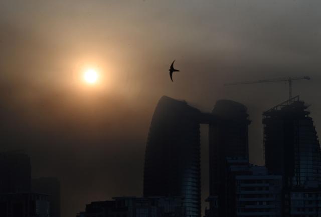 A bird flies as smoke rises over Kyiv following mass Russian drones and missile strikes on the Ukraine's capital on July 4, 2025, amid the Russian invasion of Ukraine. (Photo by Sergei SUPINSKY / AFP)