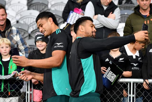 New Zealand's Tupou Vaa’i (L) and Ardie Savea take selfies for fans after the New Zealand captains' run at Forsyth Barr Stadium in Dunedin on July 4, 2025, ahead of their three-match international rugby series against France, with the first Test match to be played in Dunedin on July 5. (Photo by Sanka Vidanagama / AFP)