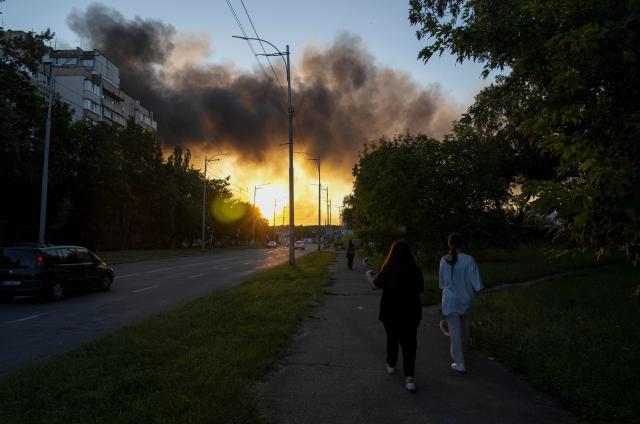 Women walk dog as smoke rises over Kyiv following mass Russian drones and missile strikes on the Ukraine's capital on July 4, 2025, amid the Russian invasion of Ukraine. Ukraine said Russia had launched 550 drones and missiles at the war-battered country overnight, as the Kremlin steps up aerial attacks and US-led peace talks stall. The Ukrainian air force said Moscow had launched 539 drones and 11 missiles, adding that air defence units had downed 268 drones and two missiles. (Photo by OLEKSII FILIPPOV / AFP)