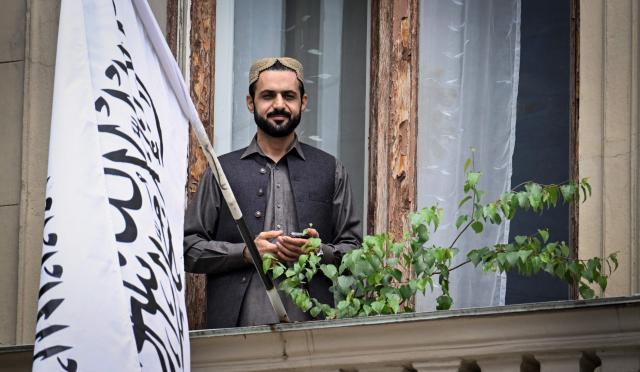 An official stands next to the flag of the Islamic Emirate of Afghanistan on the balcony of the Afghan embassy in Moscow on July 4, 2025. Russia became the first country to recognise the Taliban's rule in Afghanistan. The Taliban swept back to power in 2021 after ousting the foreign-backed government and have imposed an austere version of Islamic law. (Photo by Alexander NEMENOV / AFP)
