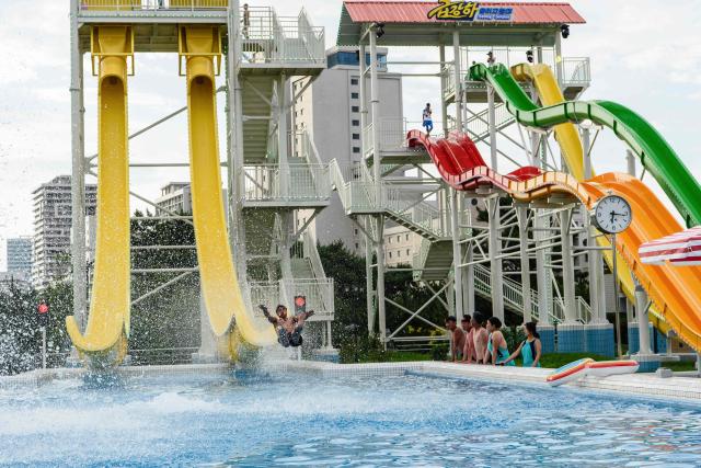 Domestic tourists watch as a man uses a slide into a swimming pool at the Myongsasimni Water Park in the Wonsan Kalma Coastal Tourist Area in Wonsan, North Korea's Kangwon Province on July 2, 2025. North Korea opened a massive resort area on its east coast, state media said on July 2, with the tourism pet project of leader Kim Jong Un reportedly set to welcome Russian guests later this month. (Photo by KIM Won Jin / AFP)